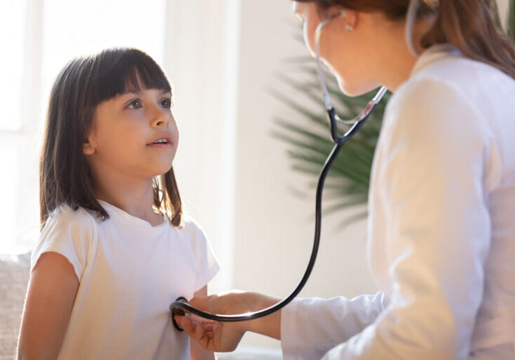 Pediatrician doctor in white uniform listening to lung and heart sound of little girl, child, patient with stethoscope, physician checkup at home or in hospital, children medical insurance care